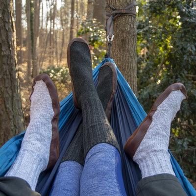 The Original Slipper Sock in Charcoal and Light Gray On Male and Female Models Sitting in Hammock