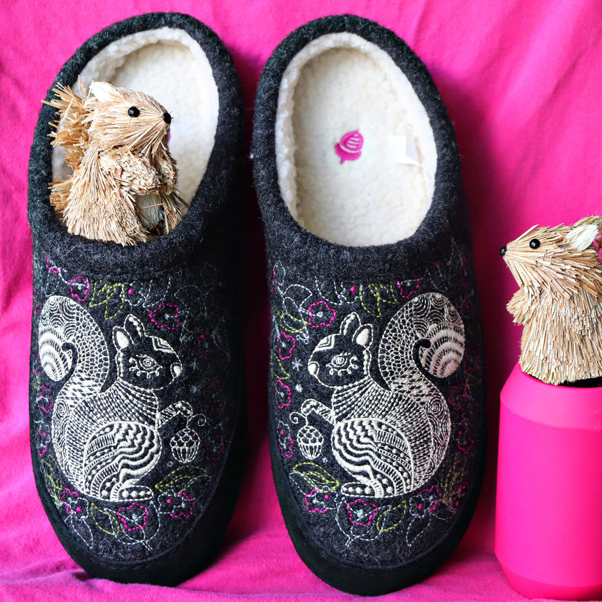 Women's Forest Mule gray squirrel Slippers sitting on pink fabric with squirrel wood figures