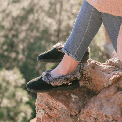 Women's Faux Fur Collar Slippers in Black on Model Sitting on a Rock While Hiking